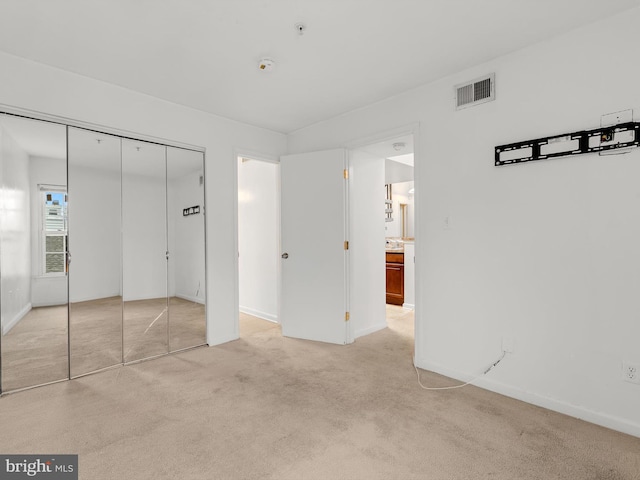 unfurnished bedroom with light colored carpet and a closet