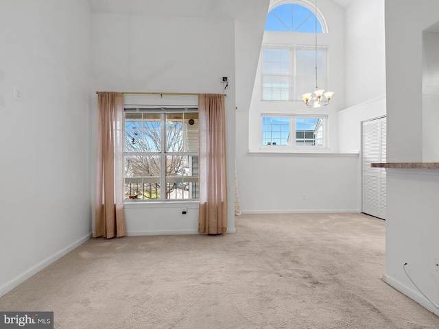 interior space featuring carpet, a towering ceiling, and a chandelier