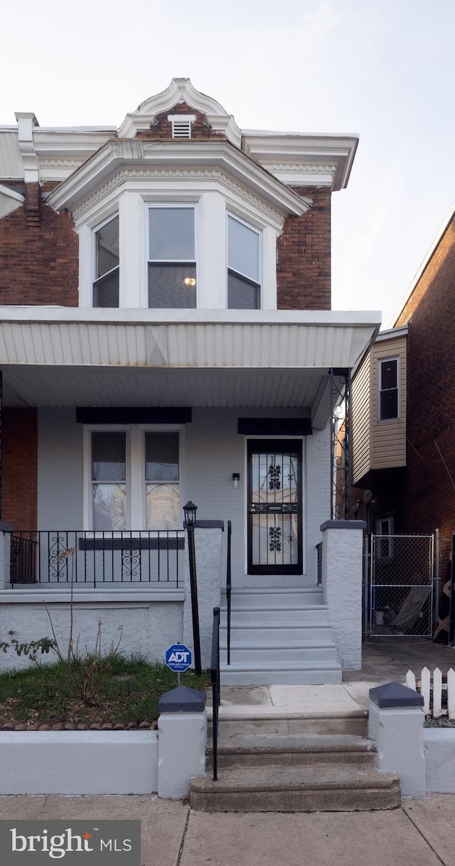 view of property featuring a porch and brick siding