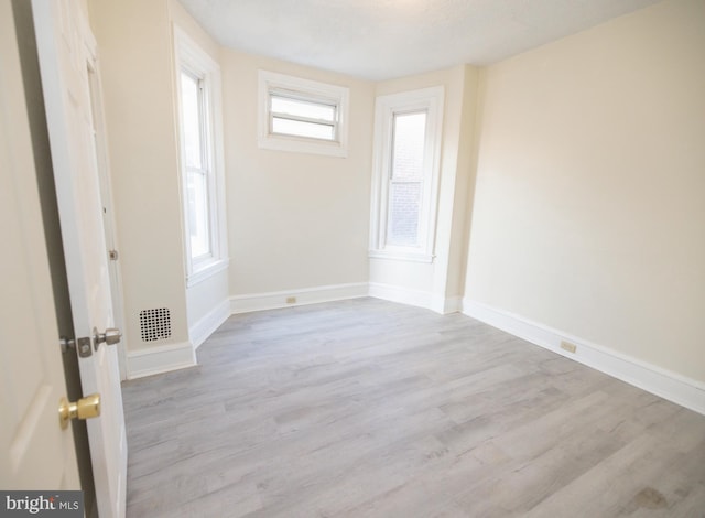 unfurnished room with visible vents, wood finished floors, and baseboards