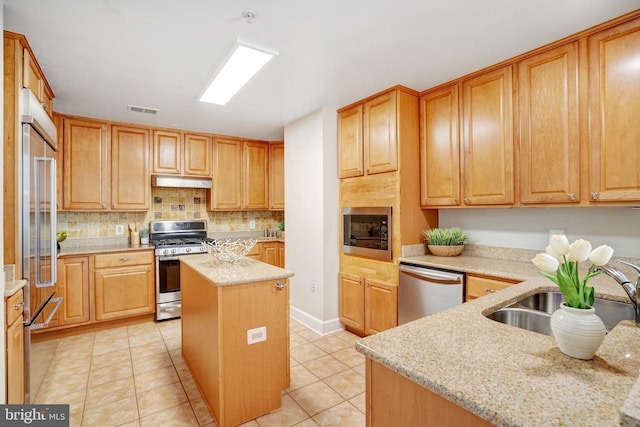 kitchen featuring built in appliances, a center island, light stone countertops, and light tile patterned floors