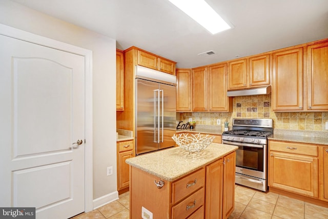 kitchen featuring a center island, stainless steel appliances, light stone counters, and light tile patterned flooring