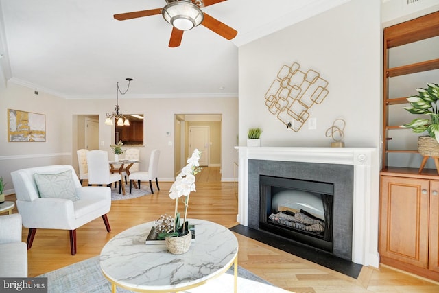 living room featuring light hardwood / wood-style floors, ceiling fan with notable chandelier, and ornamental molding