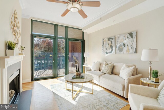 living room with ceiling fan, light hardwood / wood-style flooring, crown molding, and a wall of windows