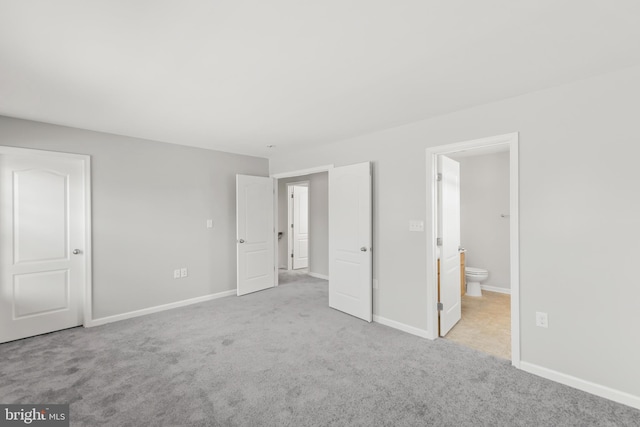 unfurnished bedroom with ensuite bathroom and light colored carpet