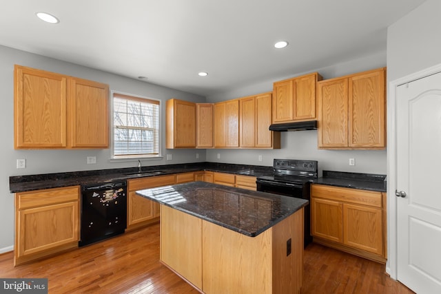 kitchen featuring a center island, sink, dark stone countertops, wood-type flooring, and black appliances