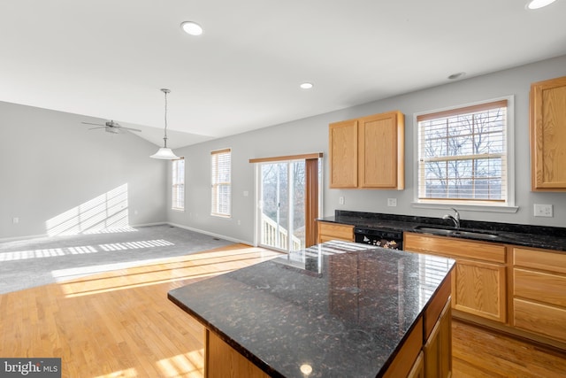 kitchen with pendant lighting, sink, light hardwood / wood-style flooring, black dishwasher, and a kitchen island