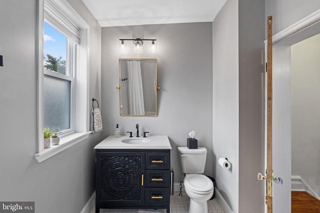 bathroom with vanity, toilet, and a healthy amount of sunlight