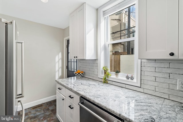 kitchen with white cabinetry, light stone counters, stainless steel appliances, and decorative backsplash