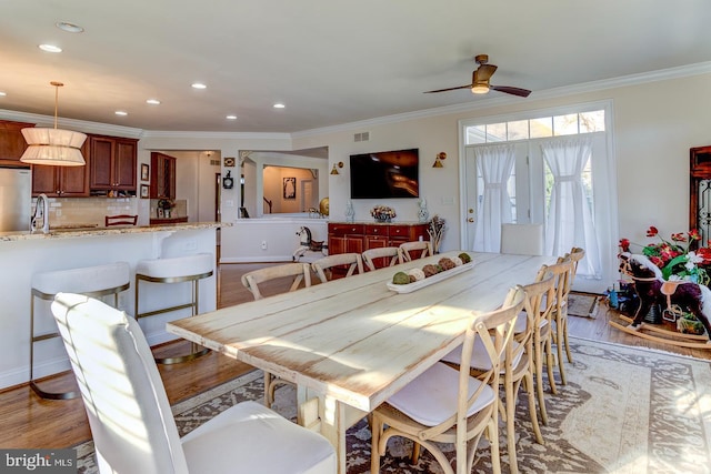 dining space featuring ceiling fan, light wood-type flooring, and crown molding