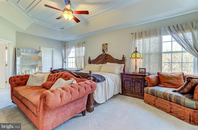 carpeted bedroom with a raised ceiling and ceiling fan