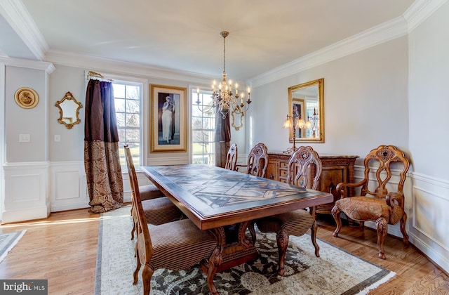 dining space featuring light hardwood / wood-style floors, crown molding, and a chandelier