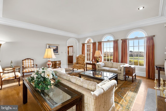 living room featuring arched walkways, crown molding, and light wood-style flooring