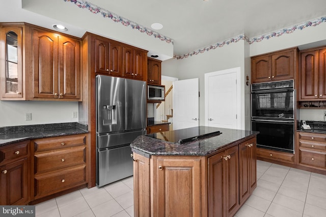 kitchen featuring glass insert cabinets, dark stone countertops, black appliances, and light tile patterned floors