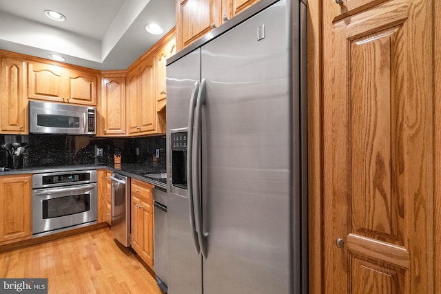 kitchen with light wood finished floors, brown cabinetry, stainless steel appliances, backsplash, and recessed lighting