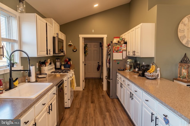 kitchen with white cabinetry, sink, dark hardwood / wood-style flooring, vaulted ceiling, and appliances with stainless steel finishes