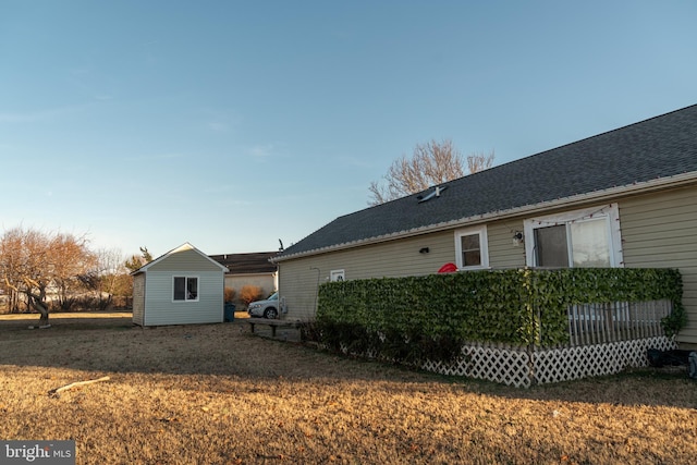 view of side of property with a deck, a storage shed, and a lawn