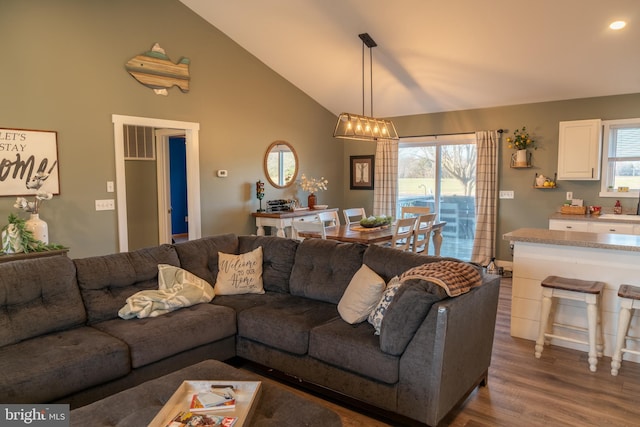 living room with a chandelier, high vaulted ceiling, and dark wood-type flooring