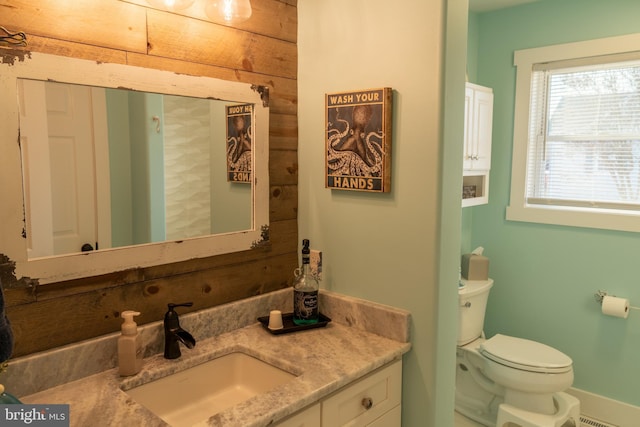 bathroom featuring wooden walls, vanity, and toilet