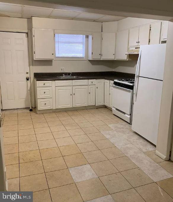 kitchen with light tile patterned floors, white appliances, white cabinetry, and sink