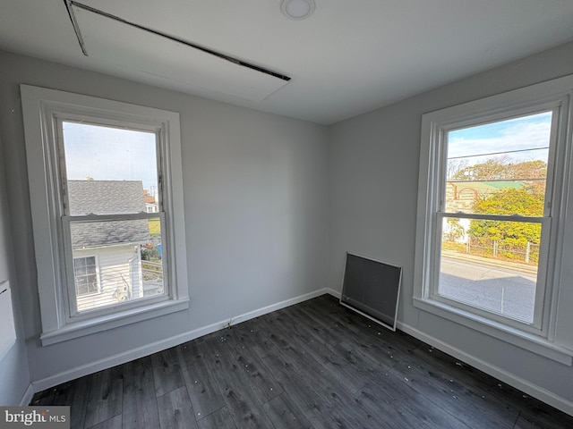 empty room with dark hardwood / wood-style flooring and plenty of natural light