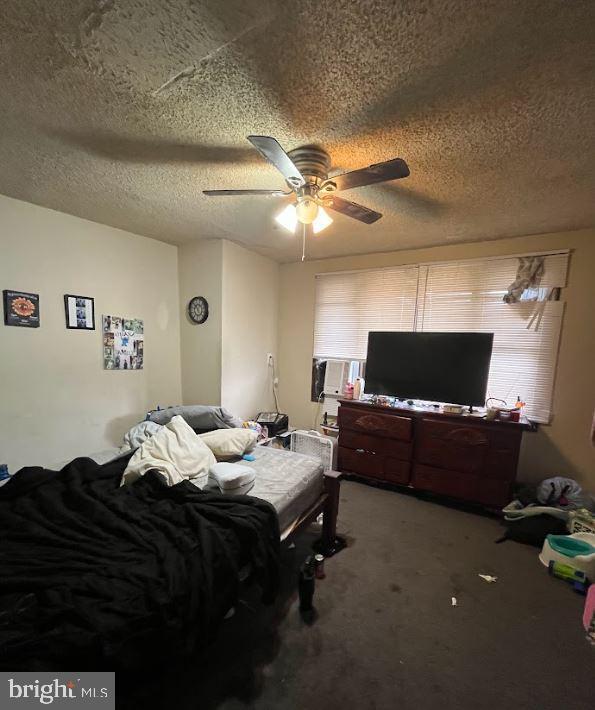 bedroom featuring ceiling fan, carpet floors, and a textured ceiling