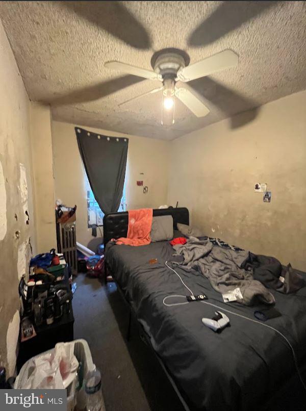 bedroom with radiator heating unit, a textured ceiling, and ceiling fan