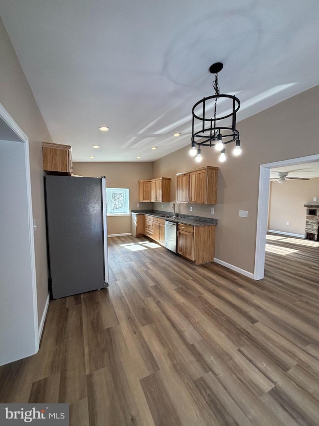 kitchen featuring wood-type flooring, appliances with stainless steel finishes, sink, and decorative light fixtures