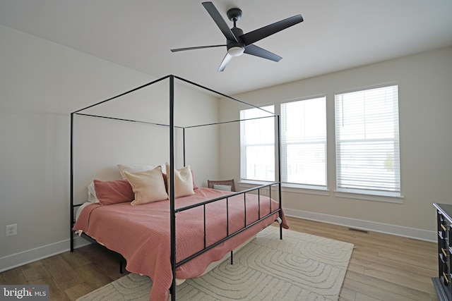 bedroom featuring hardwood / wood-style floors, ceiling fan, and multiple windows