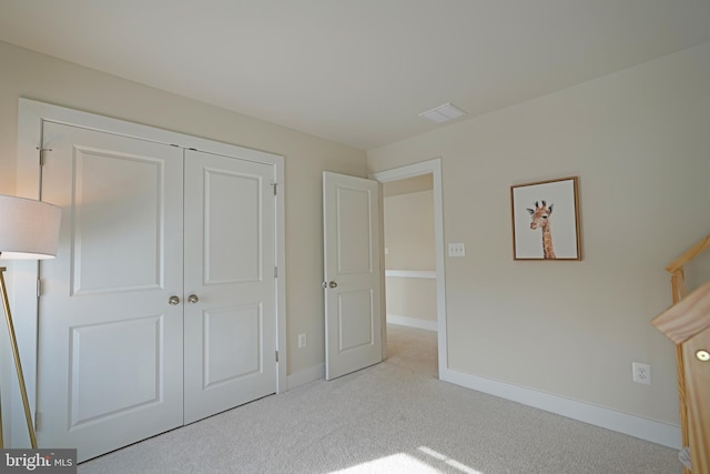 unfurnished bedroom with light colored carpet and a closet