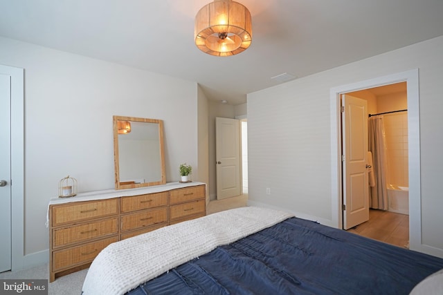 bedroom featuring connected bathroom and light hardwood / wood-style flooring