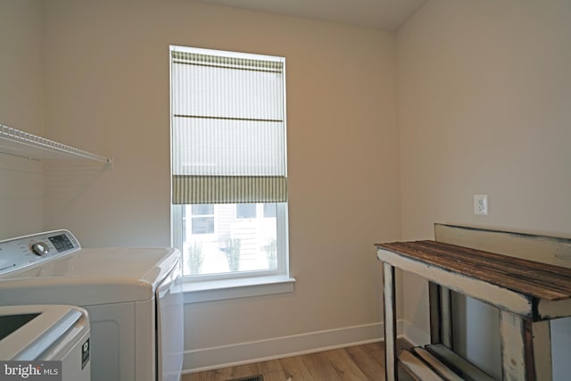 laundry area with light hardwood / wood-style floors and washer and clothes dryer