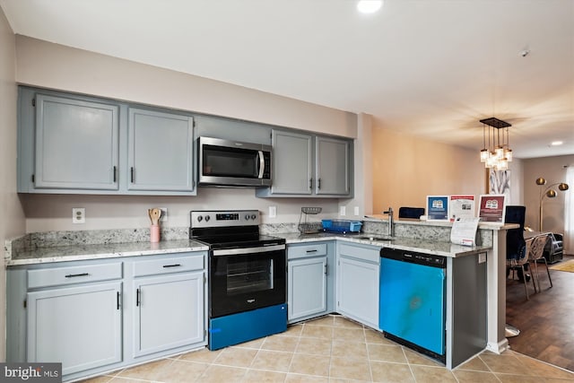 kitchen with sink, a notable chandelier, kitchen peninsula, pendant lighting, and appliances with stainless steel finishes