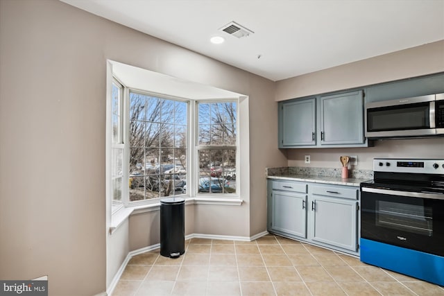 kitchen with light tile patterned floors, a healthy amount of sunlight, and appliances with stainless steel finishes