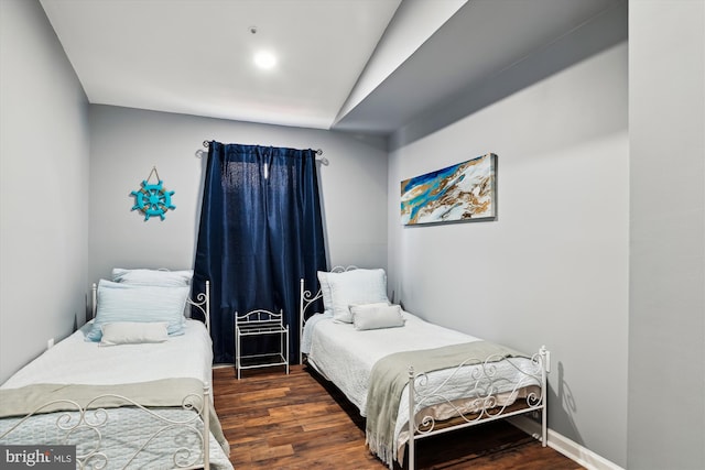 bedroom with vaulted ceiling and dark hardwood / wood-style floors