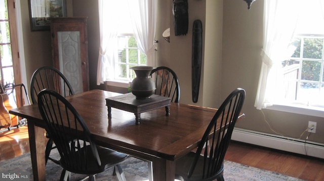 dining area featuring hardwood / wood-style floors, plenty of natural light, and a baseboard radiator