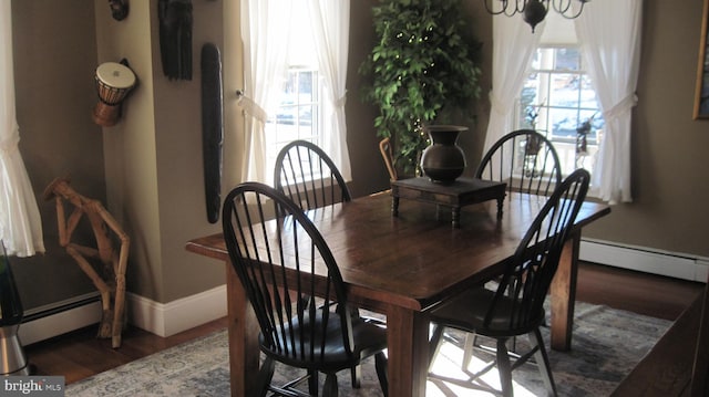 dining area featuring dark wood-type flooring, an inviting chandelier, and a baseboard heating unit