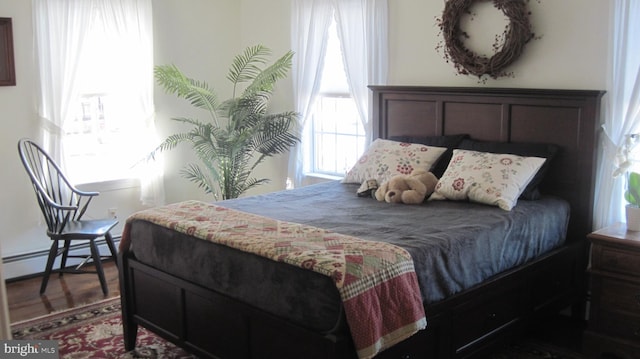 bedroom with wood-type flooring and baseboard heating