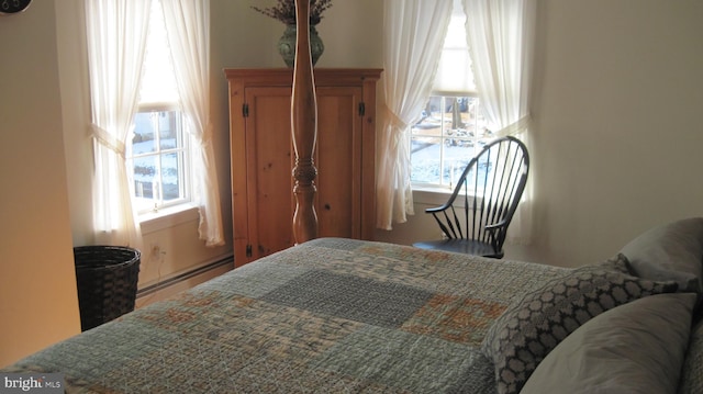 bedroom featuring multiple windows and a baseboard heating unit