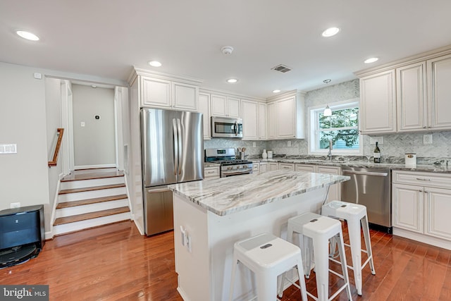 kitchen with a center island, a kitchen bar, white cabinetry, and appliances with stainless steel finishes