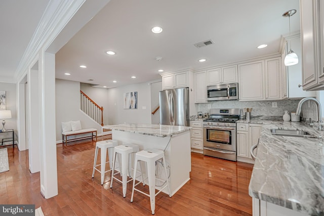 kitchen with pendant lighting, white cabinets, sink, appliances with stainless steel finishes, and a kitchen island