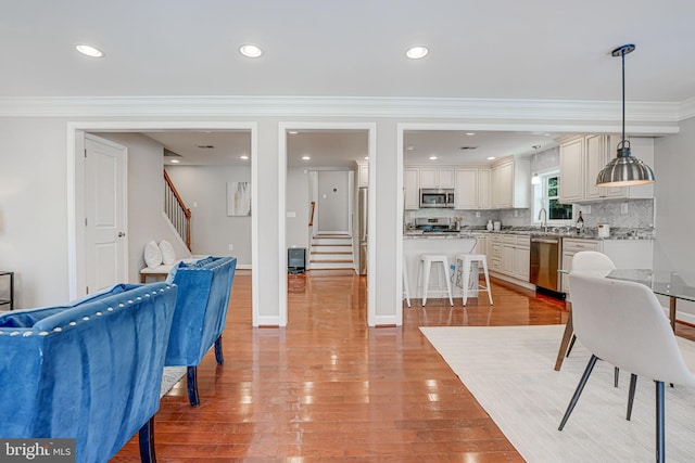 dining space featuring ornamental molding, sink, and light hardwood / wood-style flooring