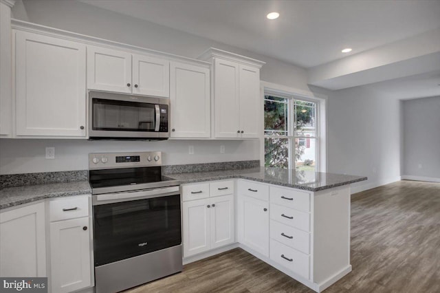 kitchen featuring white cabinets, stone countertops, dark hardwood / wood-style flooring, kitchen peninsula, and stainless steel appliances