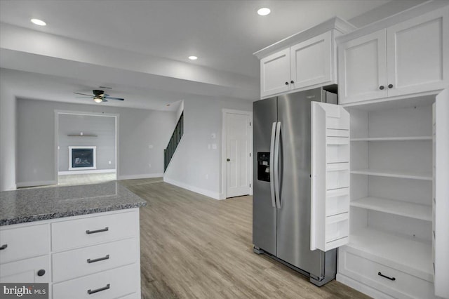 kitchen featuring white cabinetry, ceiling fan, stainless steel refrigerator with ice dispenser, dark stone counters, and light hardwood / wood-style floors