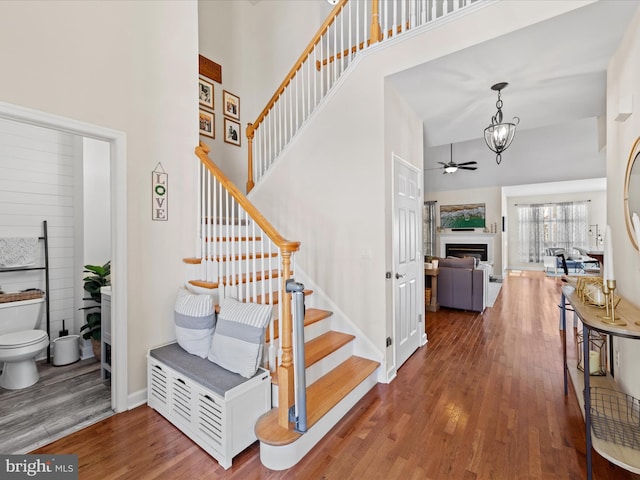 stairway featuring ceiling fan, a towering ceiling, and hardwood / wood-style flooring