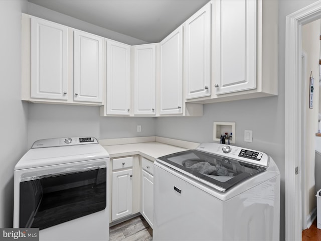 clothes washing area with cabinets, light wood-type flooring, and independent washer and dryer