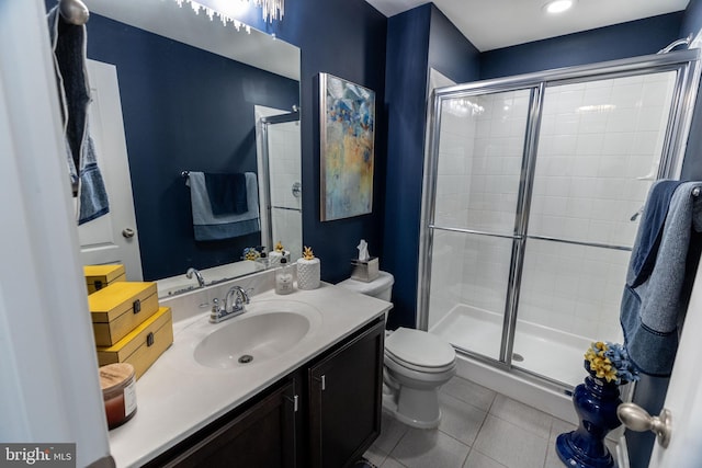 bathroom with tile patterned floors, vanity, a shower with shower door, and toilet