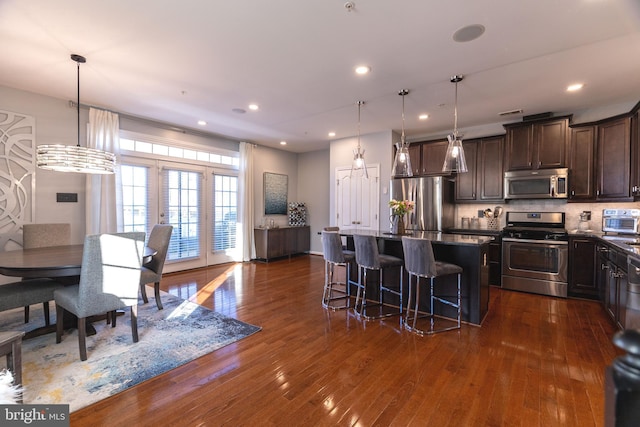 kitchen with a breakfast bar, a center island, dark wood-type flooring, stainless steel appliances, and a chandelier