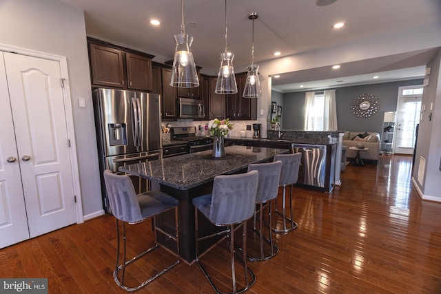 kitchen with a breakfast bar, appliances with stainless steel finishes, backsplash, and dark brown cabinets