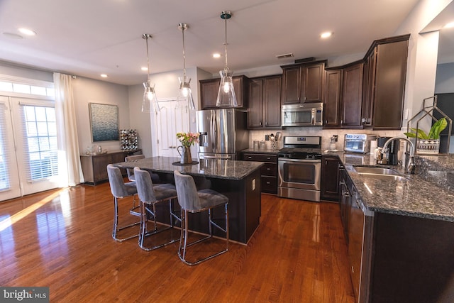 kitchen featuring a center island, dark hardwood / wood-style flooring, stainless steel appliances, and dark stone counters